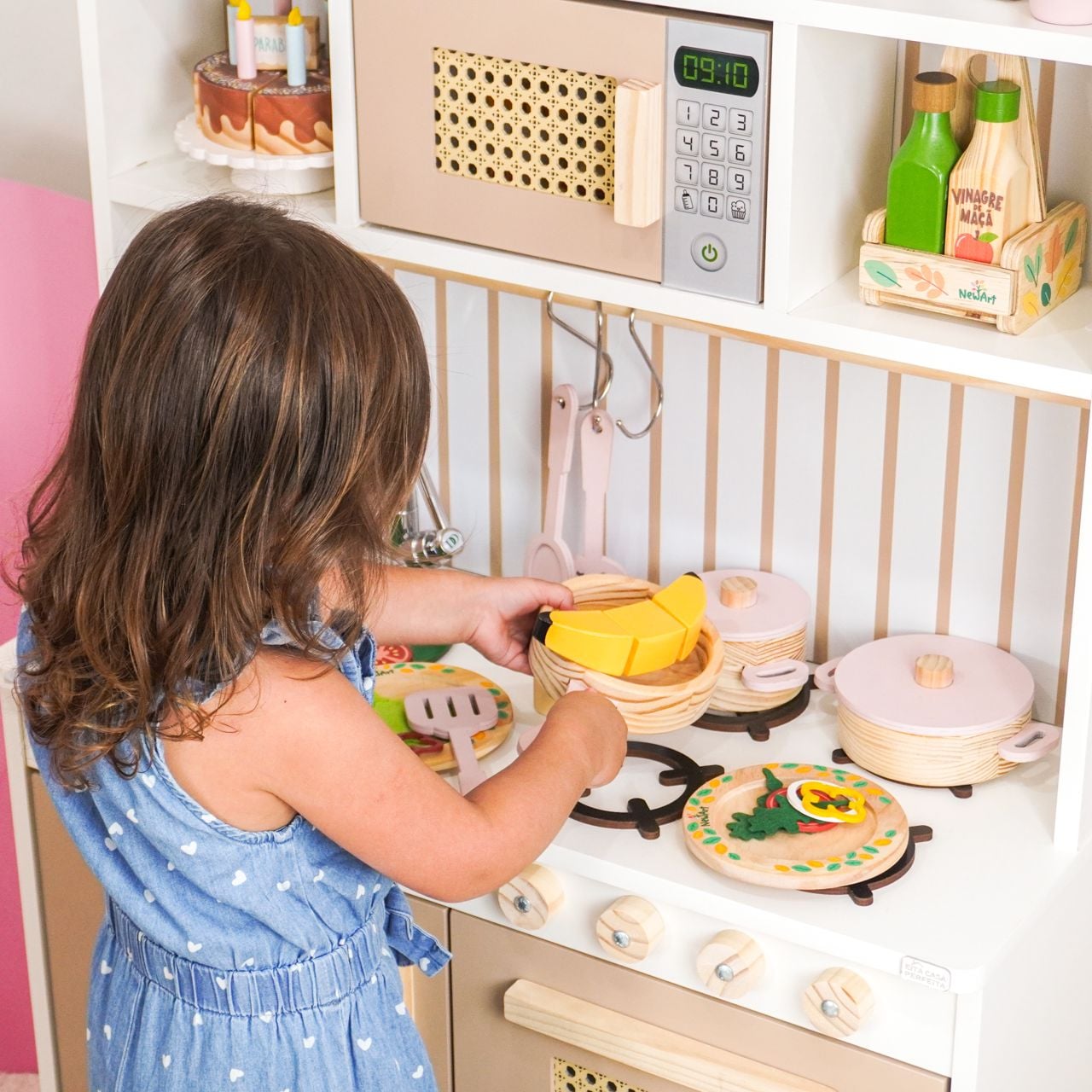 Criança brincando de cozinhar em uma cozinha infantil de madeira
