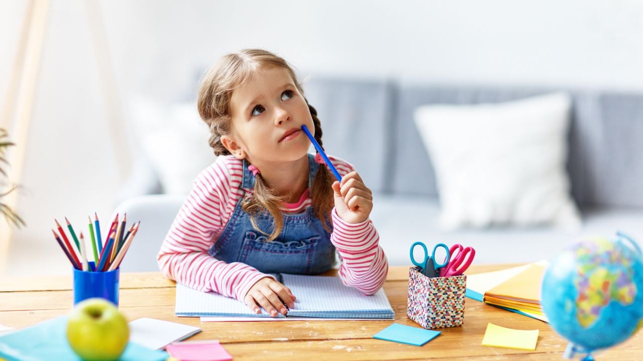 Criança sentada à mesa com lápis de cor e materiais criativos, representando ideias para incentivar a criatividade infantil em casa.