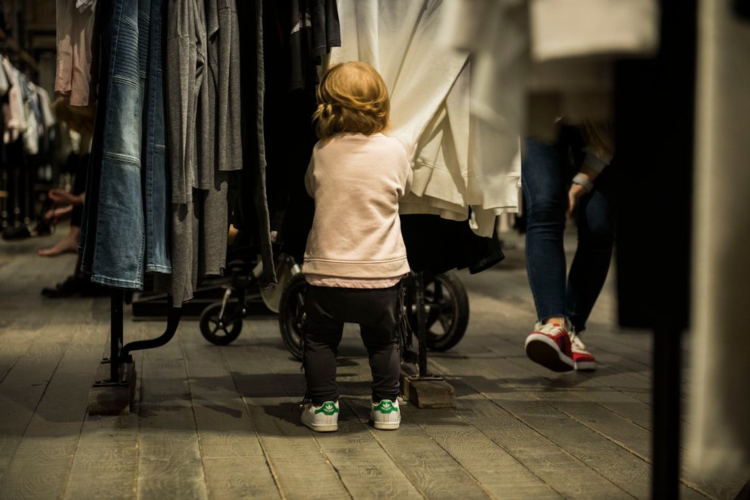 Menina pequena parada diante de roupas penduradas — autonomia no vestir crianças pequenas