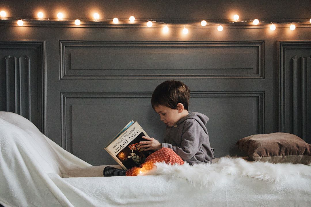 Menino lendo livro numa cama aconchegante — canto de leitura infantil em casa