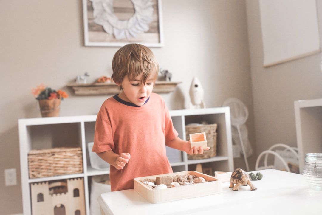 Menino brincando de cozinha ao lado de mesa de madeira com cupcakes — como escolher cozinha infantil