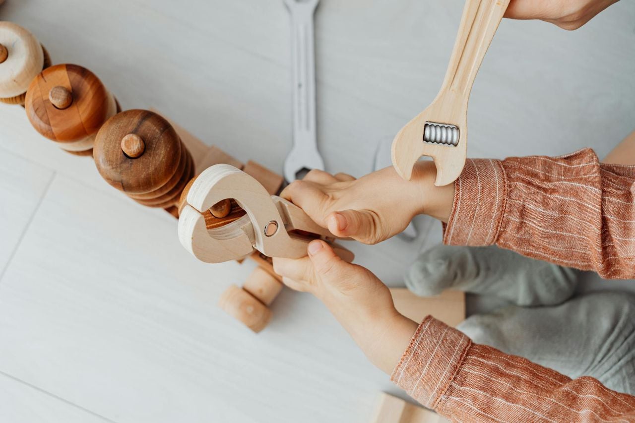 Criança brincando com ferramentas de madeira de brinquedo — espaço maker em casa para crianças de 5 anos