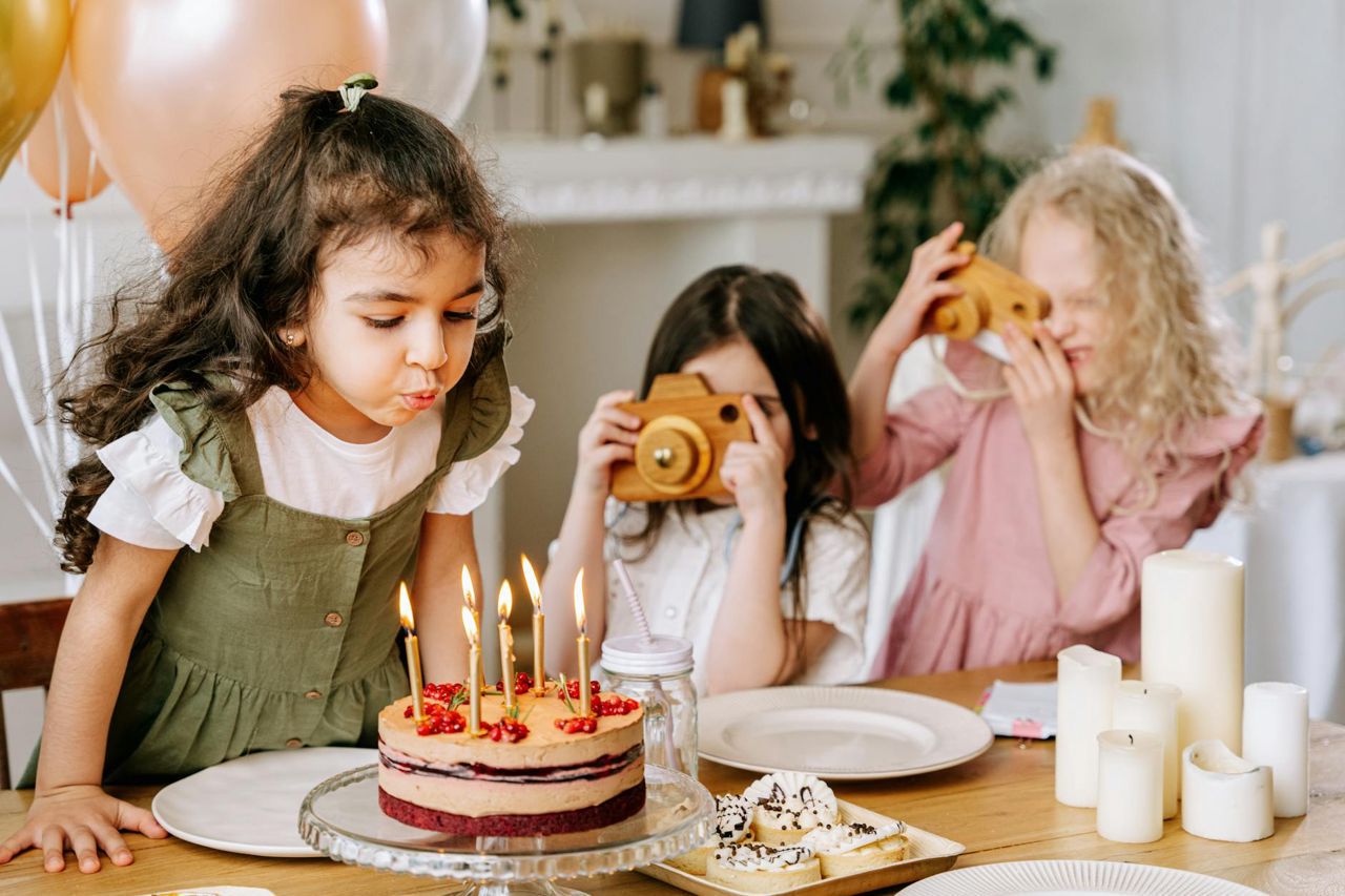 Três crianças comemorando festa de aniversário com bolo — inspiração para temas de festa infantil Montessori