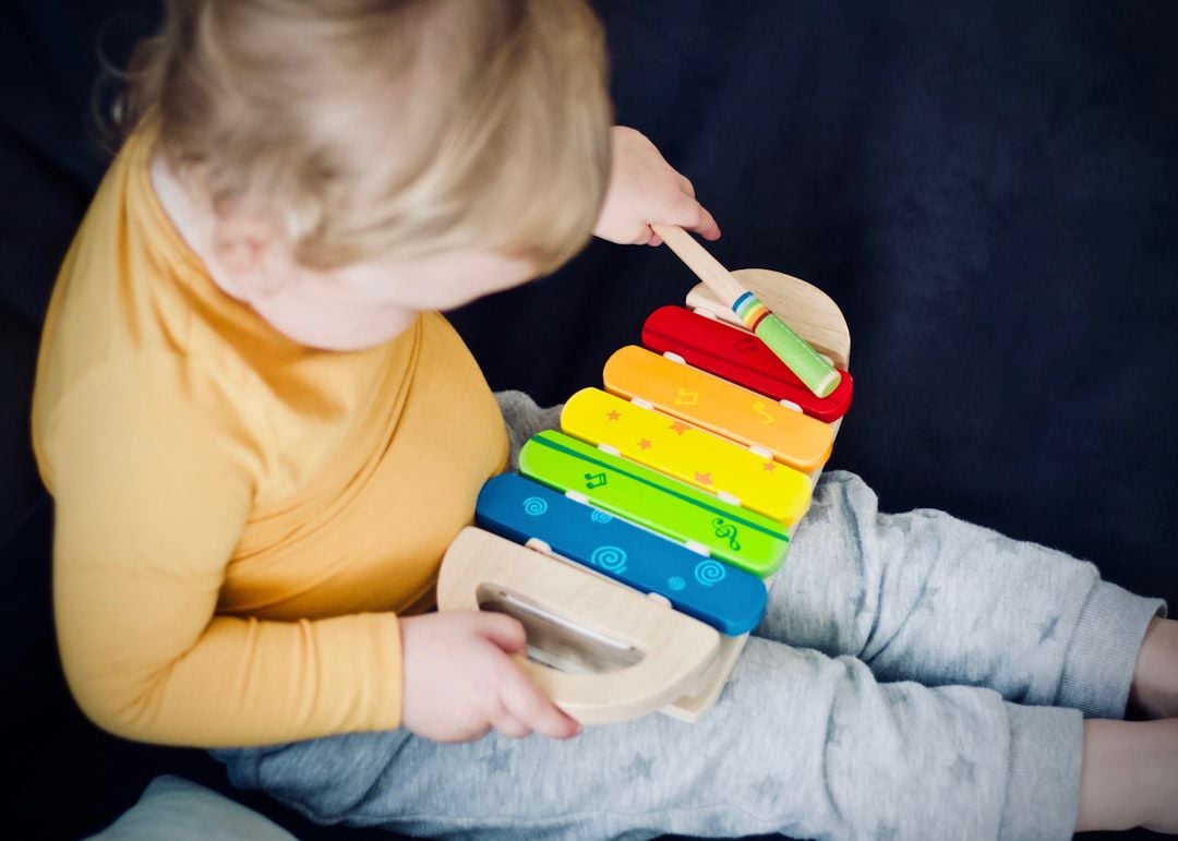 Criança pequena tocando xilofone de madeira colorido — instrumentos musicais infantis de madeira