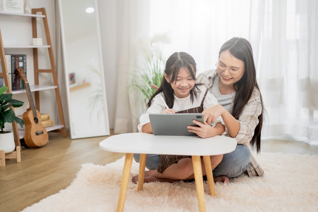 Mãe e filha sentadas no chão navegando em tablet para escolher loja online de móveis infantis confiável