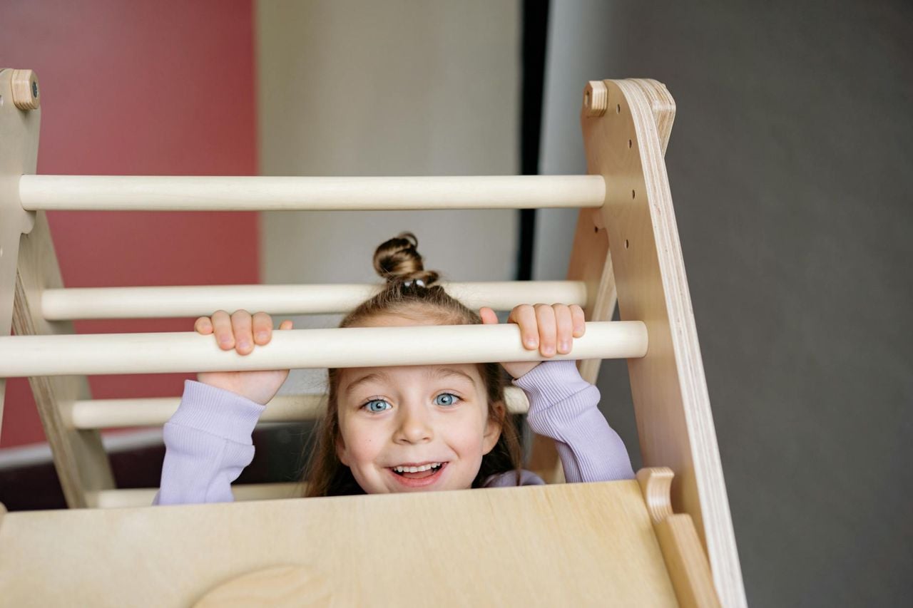 Menina brincando e escalando uma estrutura de madeira indoor — atividades de motora grossa para crianças em apartamento