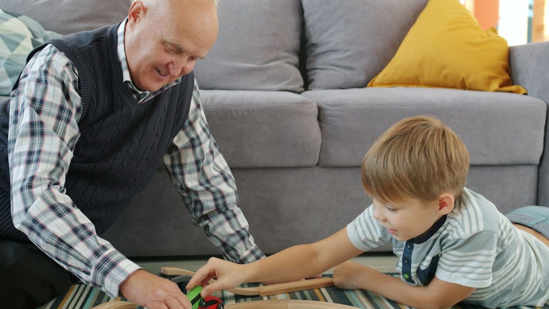 Avô e neto brincando juntos com trem de madeira — presente educativo para avós darem aos netos