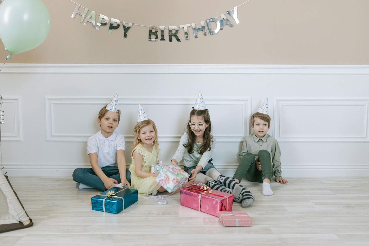 Crianças com chapéu de festa celebrando e trocando presentes — ideias para festa de fim de ano infantil