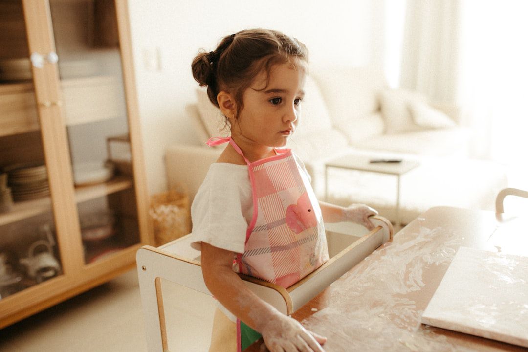 Menina pequena usando rolo de massa com farinha — atividade de vida prática Montessori para 2 anos